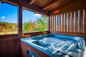 a jacuzzi tub in a room with a window at Bearfoot Pines - True Log Cabin - Wi-Fi, Hot Tub, Fishing, Deck with views! - Mins to PF in Sevierville