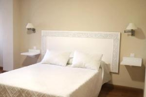 a bedroom with a white bed with two white pillows at Hotel Recio in Santa Olalla de Toledo