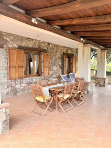 a patio with a table and chairs and a stone wall at Villa Irmā in Tertenìa
