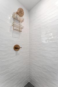 a white tiled bathroom with a shower with a shelf at Rosé Retreat: Luxurious Getaway for 6, Hot Tub, Steps to Main Street in Fredericksburg +20 photos