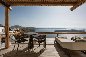 a balcony with a table and chairs and a view of the ocean at Aqua Luxury Suites by NOMÉE Hospitality Group in Imerovigli