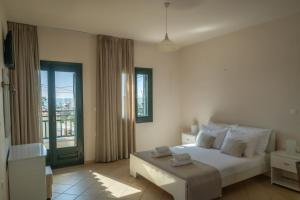 a bedroom with a white bed and a balcony at So Nice Hotel in Marathokampos