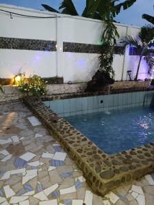 a swimming pool with a tiled floor and a building at Madibak Hotel Limbe in Limbe