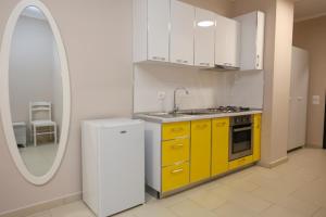 a kitchen with yellow cabinets and a sink and a mirror at Hotel Adria in Shëngjin