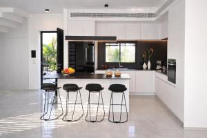 a kitchen with white cabinets and a island with bar stools at Sea 300 Villa in Migdal