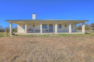 a large white house with a porch on a field at Casa Blanca: Hot-tub, Fire Pit, Hill Country Views in Luckenbach