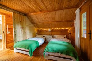 two beds in a room with wooden walls at Leśniczówka Białogóra & jacuzzi in Białogóra