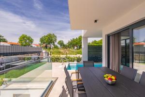 an outdoor dining area with a table and chairs and a pool at Brand new apartment with private pool in Njivice