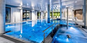 a large pool with blue water in a building at Lake Hill Studio 35- strefa wellness w cenie in Sosnówka