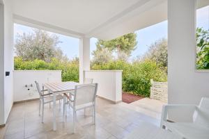 a white dining room with a table and chairs at Pilone del Monaco - Pool & Free Parking in Vieste