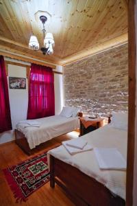 a bedroom with two beds and a brick wall at Hotel Brahimi in Gjirokastër