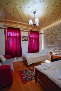 a bedroom with two beds and red curtains at Hotel Brahimi in Gjirokastër +37 photos