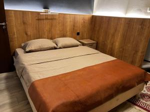 a large bed in a room with wooden walls at Hotel Lido in Prishtinë