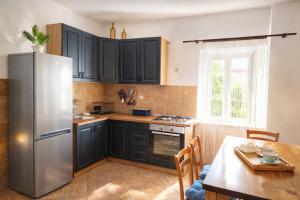 a kitchen with black cabinets and a stainless steel refrigerator at Apartmani Điran in Preko