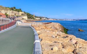 a walkway next to a body of water with rocks at Patio by the sea in Cruz Quebrada