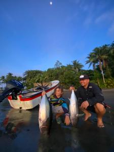 a man and a child holding their fish on the beach at Paraisurf colombia in Nuquí