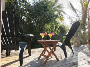 two glasses on a table on a deck with two chairs at Tialba Lodge in Sainte-Anne