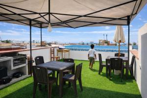a man standing on a roof with a table and chairs at Kaihalulu Beach Room - Punta Hermosa in Punta Hermosa