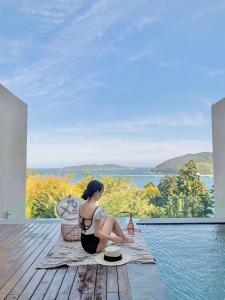 a woman sitting on a rug next to a pool at Hotel SANG SANG & Private SANG SANG POOL VILLA in Geoje