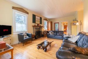 a living room with a leather couch and a tv at La Vieille École & Spa & Parc Naturel in West Brome