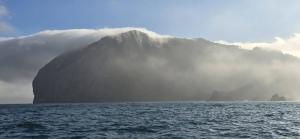 a mountain in the middle of the ocean with clouds at Apto. En Mundaka in Mundaka