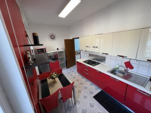a kitchen with red cabinets and a table with red chairs at Apartment house in the center in Oggiono +2 photos