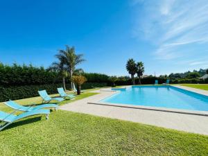 a swimming pool with two lounge chairs next to it at Villa Vieira in Alvarães
