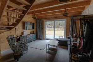 a living room with a couch and a chair and a tv at Domy nad Strugą - jacuzzi, las, wieś, rowery, kajaki in Liciążna