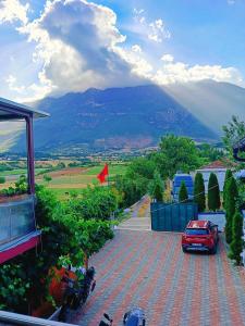 a red car parked in a parking lot with a mountain at Camping SuperPanorama in Kukës