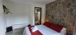 a bedroom with a bed and a stone wall at Estúdio Beija-flor Itaipava in Araras Petropolis