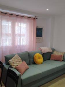 a living room with a green couch with pillows at Pretodomar2 in A Coruña
