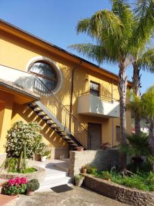 a yellow building with a staircase and palm trees at Sikelia in Santa Elisabetta