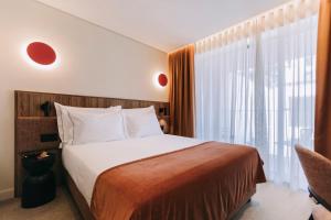 a bedroom with a bed and a large window at Hotels 705 O'Porto Hotel in Porto