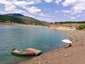 a boat on the shore of a river with an umbrella at Camping SuperPanorama in Kukës +11 photos