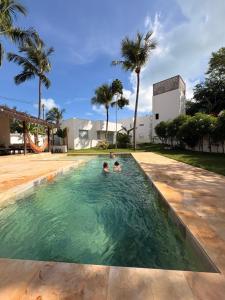 two people in a swimming pool with palm trees at Beach Front Exclusive Villa with Pool in São Miguel do Gostoso