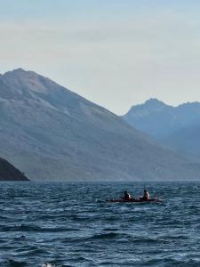 two people are sitting on a boat in the water at Camping Delta del Azul in Lago Puelo