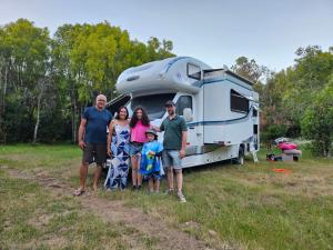 a family poses in front of their rv at Camping Delta del Azul in Lago Puelo