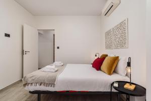 a white bedroom with a large bed with yellow and red pillows at Doormans House city center by Homeful Homes in Lisbon