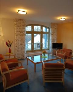 a living room with orange chairs and a glass table at Pension Am Seeberg in Alt Zeschdorf