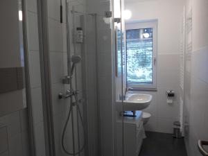 a white bathroom with a shower and a sink at Bergidylle in Kurort Oberwiesenthal +14 photos
