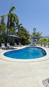 a swimming pool with chairs and a palm tree at Villa Casa blanca Con Alberca privada in Acapulco