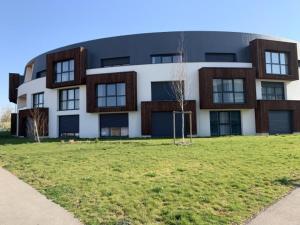 a building with a grass field in front of it at Le cocon de Joëly in Rosières-près-Troyes