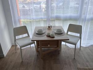 a wooden table with two chairs and a table with dishes on it at Le cocon de Joëly in Rosières-près-Troyes
