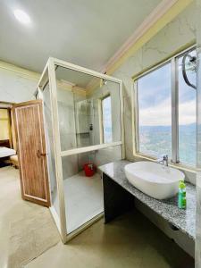 a bathroom with a sink and a shower with a window at Aizawl Hotel in Āīzawl +34 photos