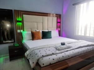 a bedroom with a large bed with purple and green lights at Riverleaf Hotels and Suites in Asaba