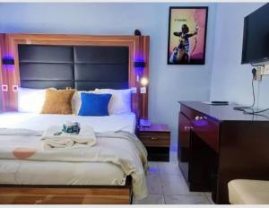 a bedroom with a bed and a desk with a television at Riverleaf Hotels and Suites in Asaba
