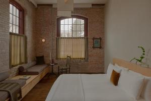 a bedroom with a large bed and a brick wall at Pocketbook Hotel and Baths in Hudson