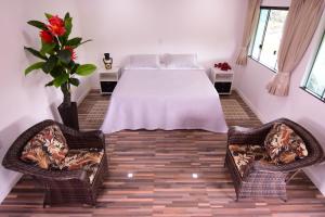 a bedroom with a white bed and two chairs at Angatu Amazon Jungle Lodge in Iranduba
