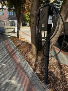 a parking meter on a sidewalk next to a tree at Štúdio Sihoť - parkovanie a nabíjanie EV in Trenčín