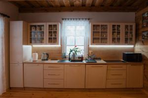 a kitchen with white cabinets and a sink and a window at Gajówka Wiry in Pawłowa